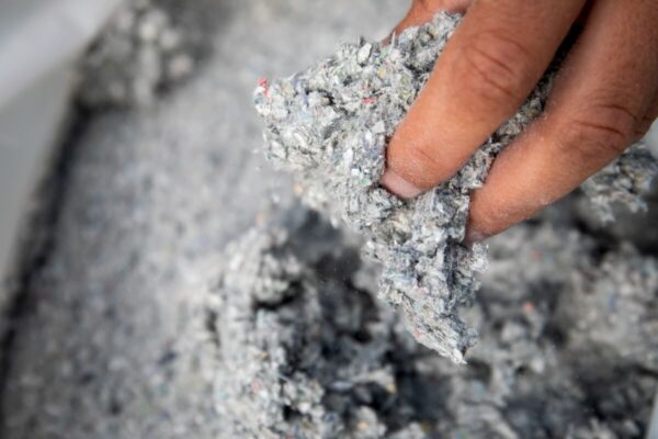 Ręka trzyma materiał używany do ocieplania celulozą.